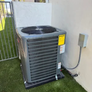 Air conditioning condenser set on a level pad with a nearby electrical disconnect