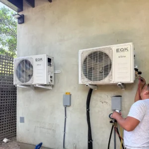Technician charging a ductless mini-split system with manifold gauges